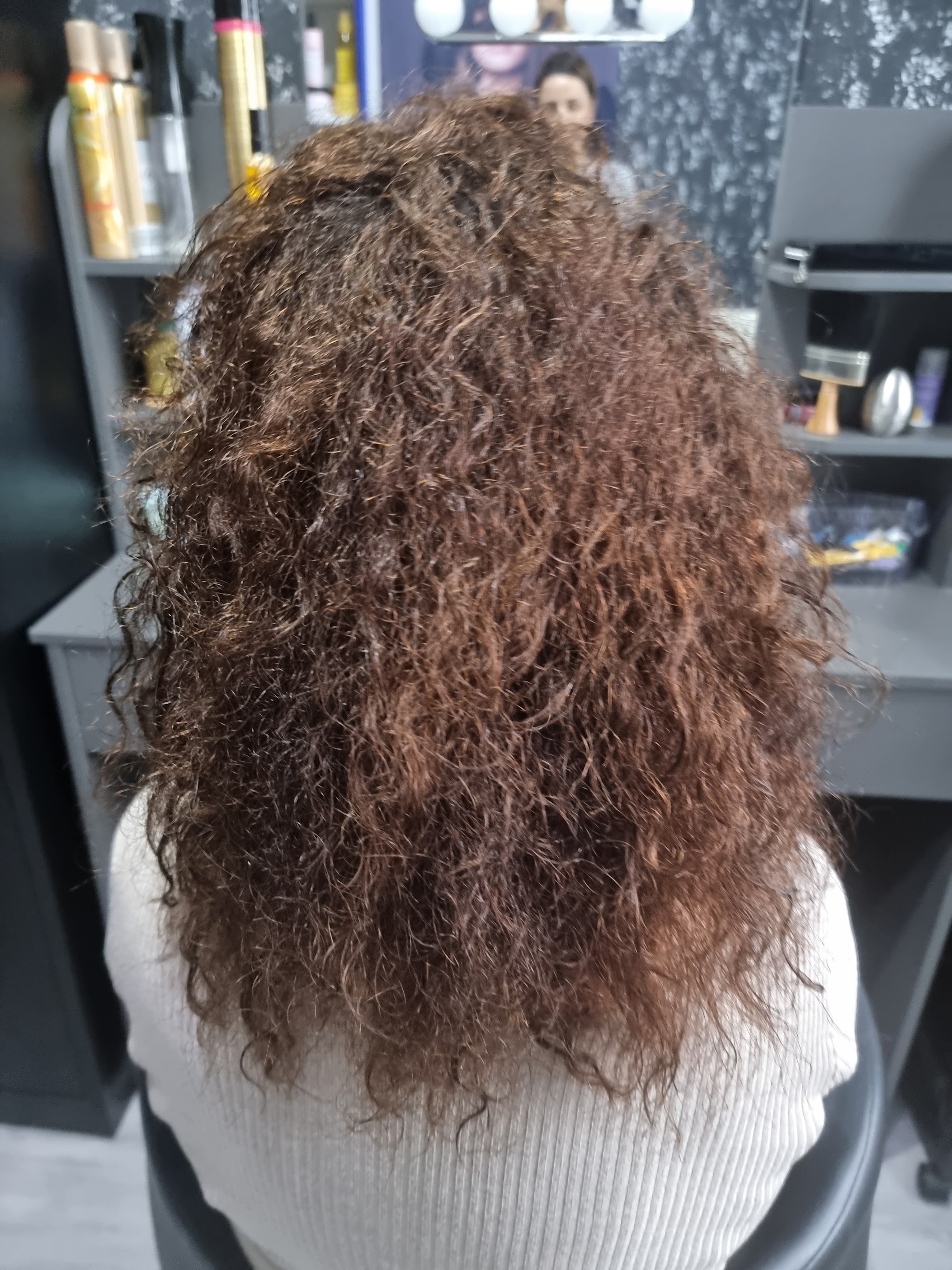 Lange bruine krullen van achteren, in de salon van Fatin